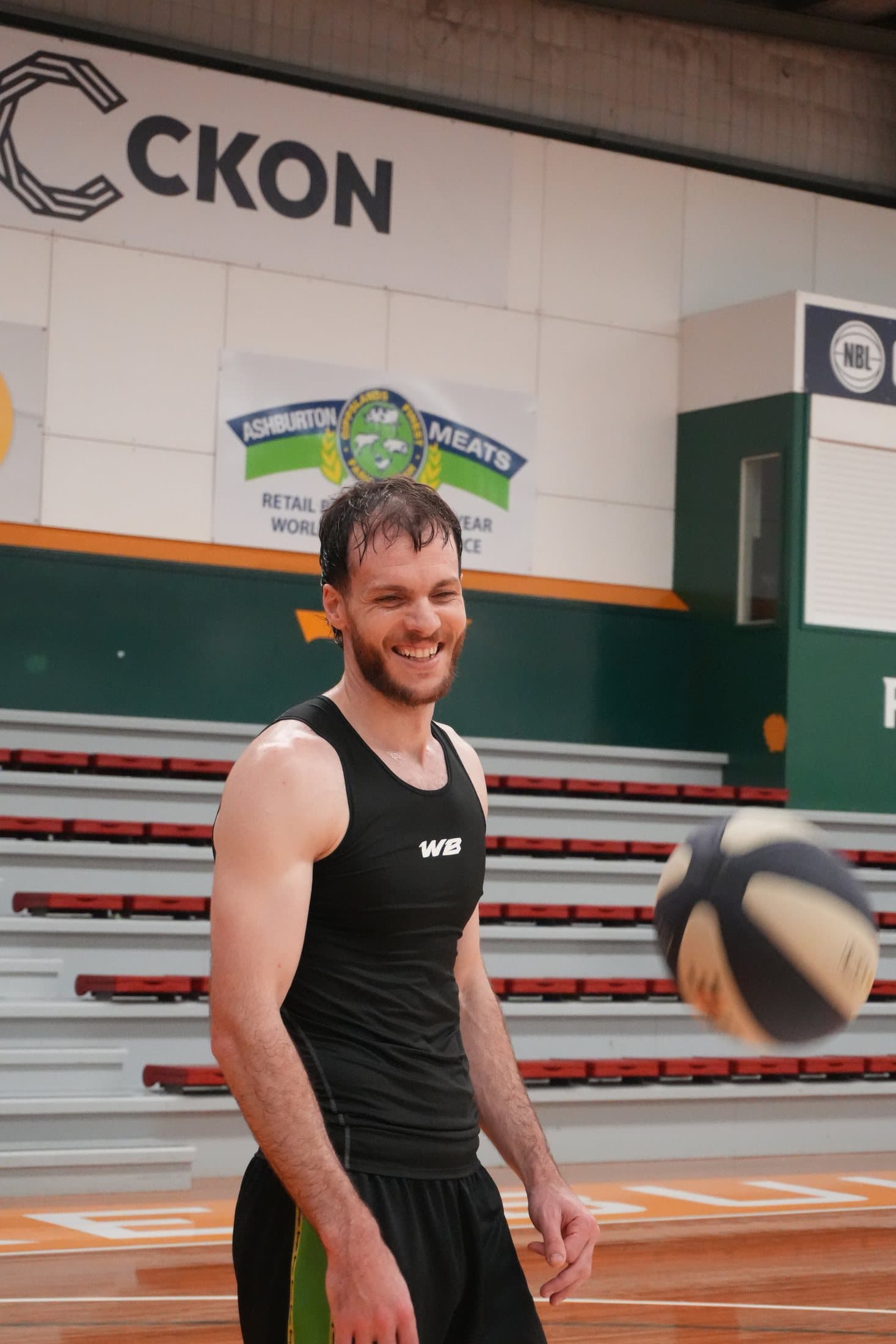 Gabe smiling on the court as a basketball spins through the air